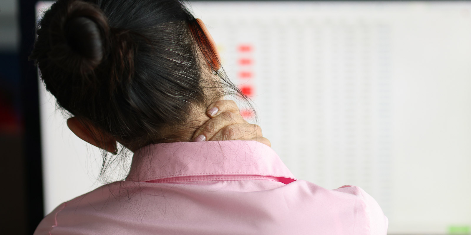tired woman sits at computer and massages pain in her neck